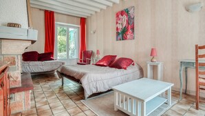 Ein Schlafzimmer mit zwei Betten, einer weißen Bank, einem kleinen Tisch und einem roten Sessel.