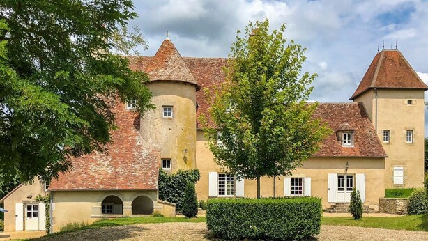Ein großes, historisches Gebäude mit einem zentralen Turm, zahlreichen Fenstern und einem Kieshof.