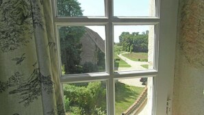 Ein Zimmer mit einem großen Fenster und Blick auf einen Garten und einen Weg.