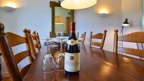 Une table à manger avec une bouteille de vin de Bourgogne Grand Ordinaire, deux verres à vin vides et une lampe.