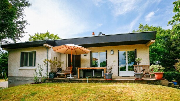 Une maison moderne dotée d’un patio, d’une table à manger et de coins salon extérieurs.