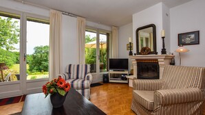 Un salon avec un canapé, un téléviseur, une cheminée et une vue sur l’extérieur.