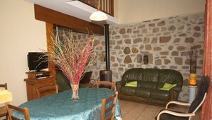 A dining area with a table set for four, a stone wall, a leather sofa, and a fireplace.