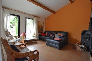 Un salon avec un canapé, des fauteuils, une cheminée et une fenêtre avec des rideaux.