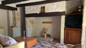Une pièce chaleureuse avec un sol à carreaux, un mur en pierre, un meuble en bois et un téléviseur.