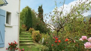 A garden with a white building, a staircase, and various plants and flowers. - Riverside Home in Folelli (Folelli)
