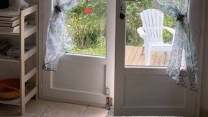 A door with a frosted glass panel and a view of a garden with red flowers. - Riverside Home in Folelli (Folelli)