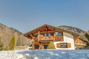 Un chalet en bois doté d’un balcon, entouré de neige et de montagnes.