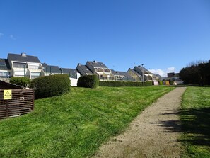 Un quartier résidentiel avec des maisons modernes, un chemin de gravier et un panneau d’avertissement.