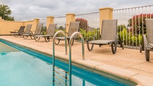 A poolside area with lounge chairs and a metal pool ladder. - Pleasant holiday home with private pool (St Nexans)