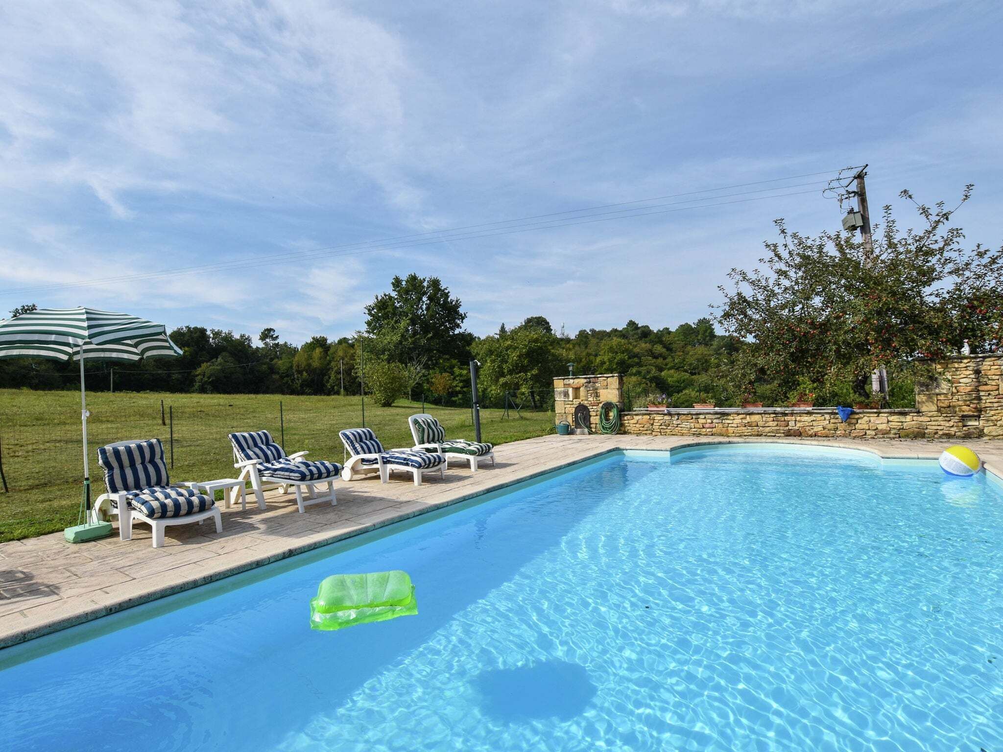 Une piscine avec des chaises longues et un mur en pierre.
