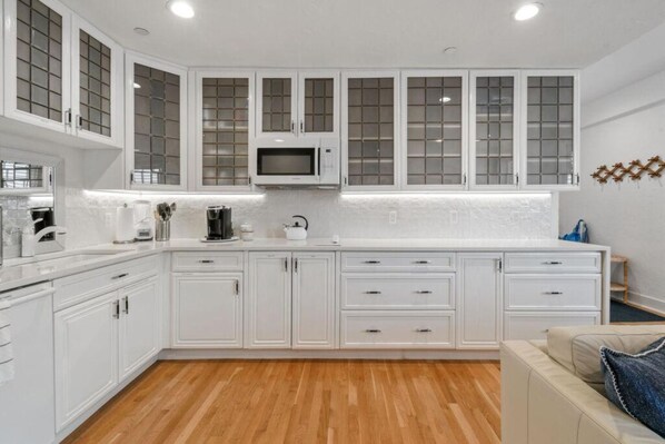 A modern kitchen with white cabinetry, a microwave, and a coffee maker.