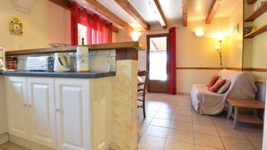 Una cocina con una isla central, armarios blancos y techo de madera.