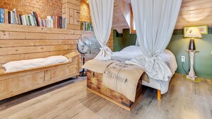 Ein gemütliches Schlafzimmer mit einem hölzernen Bett, einer Holzkommode und einem Bücherregal voller Bücher.