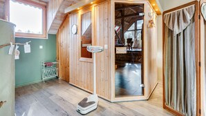 Ein Raum mit Holzboden und -ausstattung, der als Sauna genutzt wird, mit Glastür, einer Saunabank und einer weiteren Holzbank.