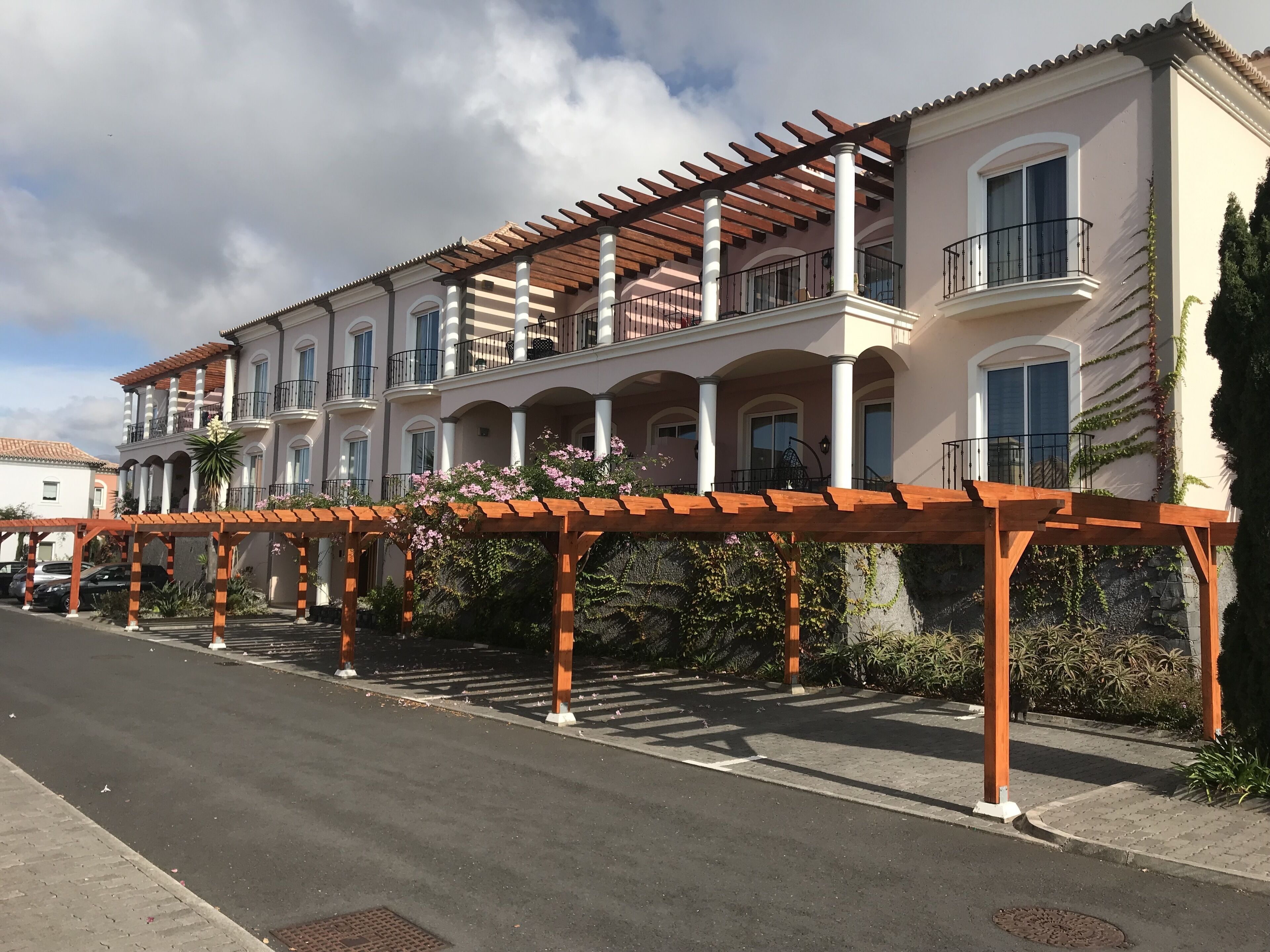 A multi-story hotel with balconies, a covered walkway, and a garden area.