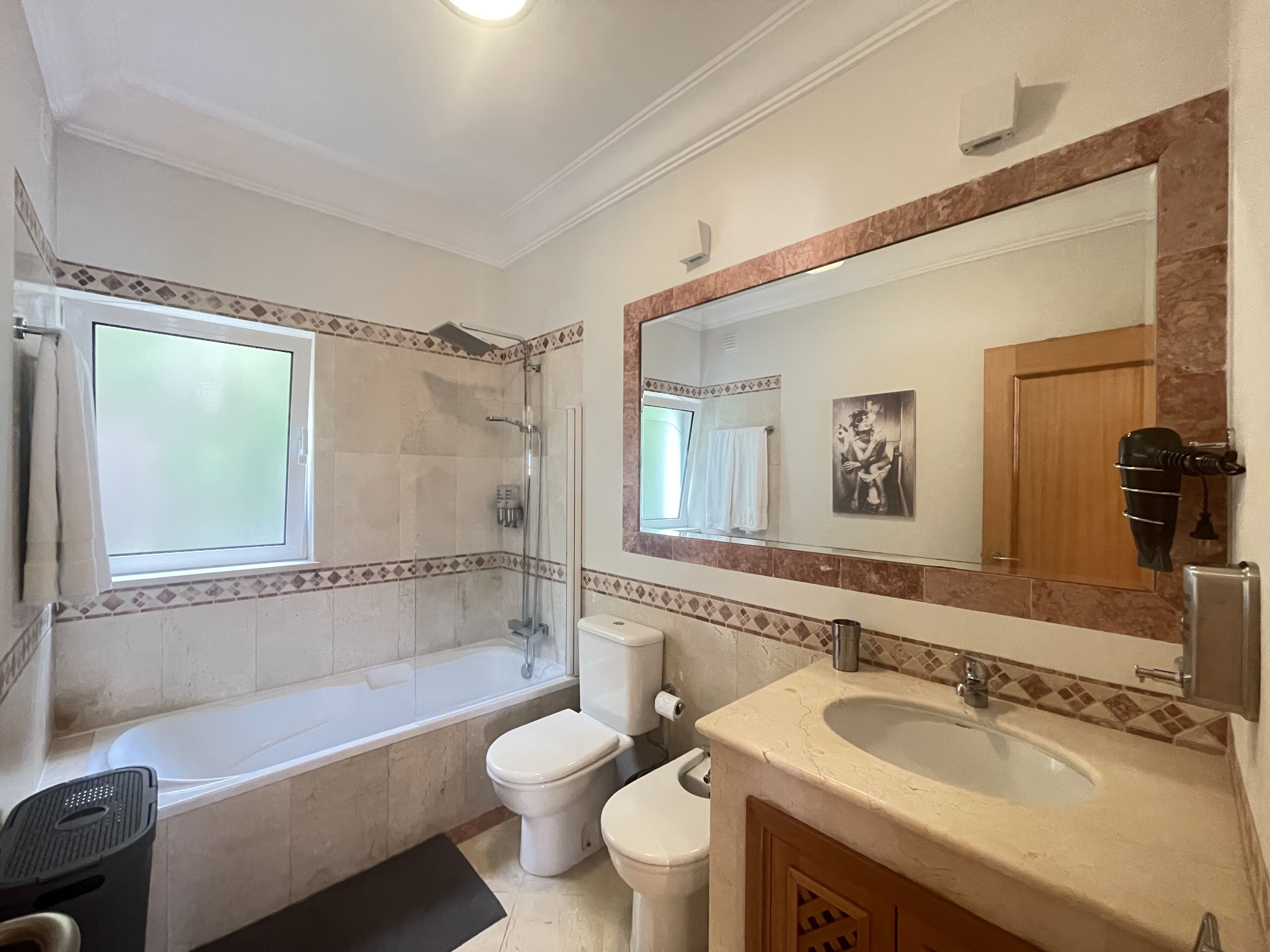 Ein Badezimmer mit Badewanne, Toilette, Waschbecken und einem großen Spiegel.
