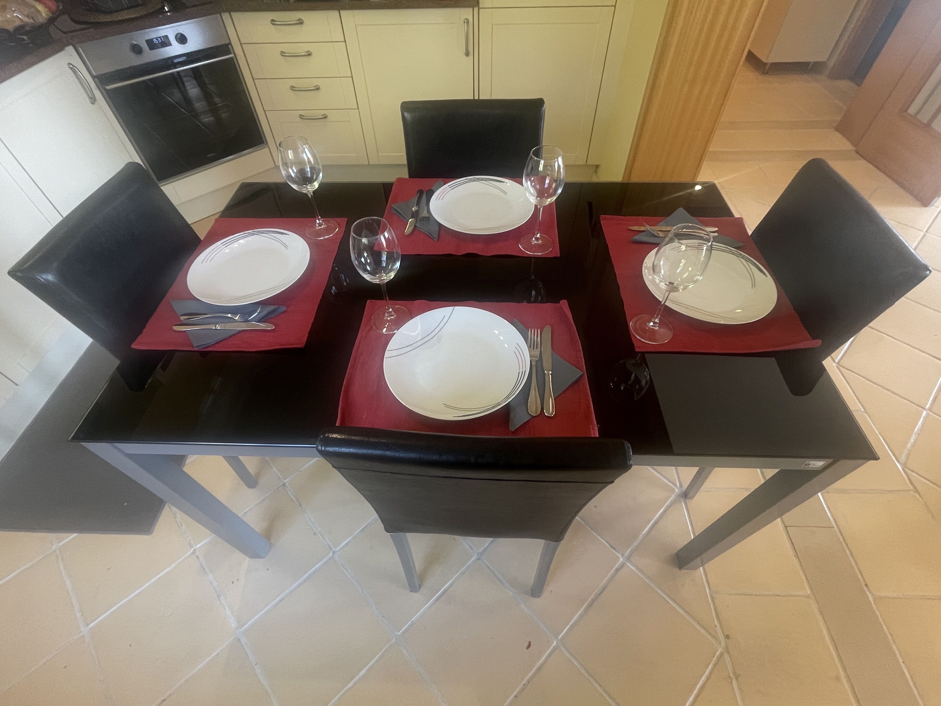 A dining table set for four with red placemats, white plates, and cutlery.