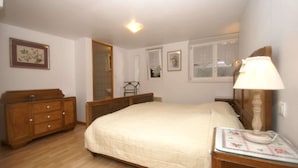 Une chambre à coucher avec un lit, une commode en bois et une table de chevet avec une lampe.