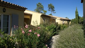A row of yellow buildings with tiled roofs, surrounded by greenery and trees.