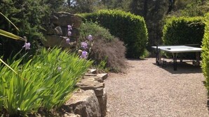 A garden pathway with a ping pong table, surrounded by neatly trimmed hedges and flowering plants. - Apartment in Montauroux with Pool & Forest Views (Montauroux)