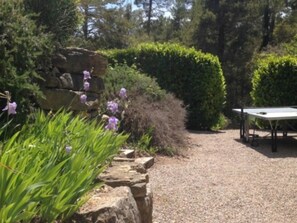 A garden with a gravel path, a table, and a rock formation.