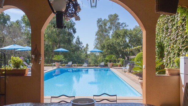 A pool area with a clear view through an archway, featuring a tiled floor, lounge chairs, and umbrellas. - Mansion in Fréjus with Private Pool (Fréjus)