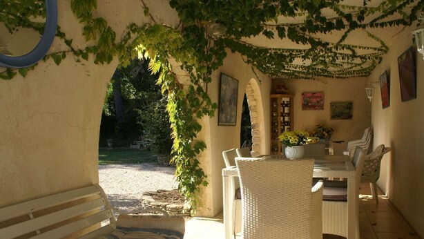 A covered patio with wicker furniture, a bench, and a table with chairs. - Holiday Home in Piolenc near Roman Orange (Piolenc)