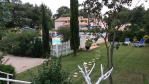 A garden with a swimming pool, white fence, and lounge chairs. - Holiday Home in Piolenc near Roman Orange (Piolenc)