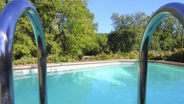Une piscine dotée de rampes métalliques et d’une plage en bois.