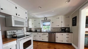 Een moderne keuken met witte kastjes, een RVS vaatwasser, een magnetron en een waterkoker.