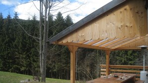 A wooden pergola with a picnic table and benches, surrounded by a forested area. - Chalet in Ventron near Ski Lift (Ventron)