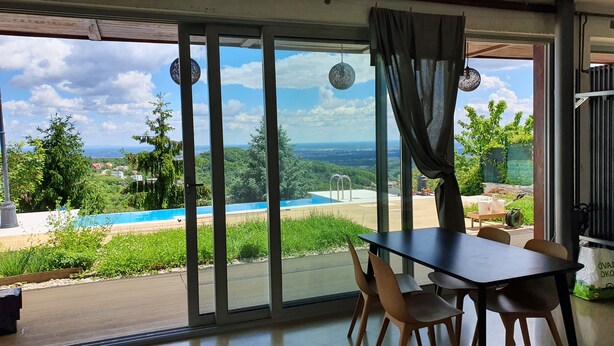 Una stanza con vista su una piscina, mobili da esterno e un tavolo.
