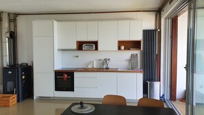 Una cucina compatta con mobili bianchi, un forno Bosch, un microonde e una finestra con vista.