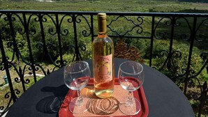 Une table avec une bouteille de vin et deux verres, le tout disposé sur un plateau, avec en arrière-plan un paysage montagneux pittoresque.