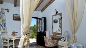 Une chambre à coucher comprenant un lit, une chaise, un bureau, un miroir et une vue sur l’extérieur.