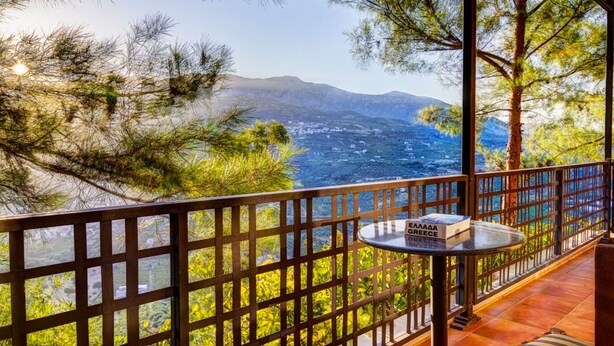 A balcony with a view of a mountainous landscape and a table with a sign reading "GREECE." - Villa Despoina in Malades (Malades)