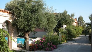 A residential street with a pool, stone pillars, and flowering plants. - Villa Despoina in Malades (Malades)