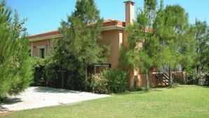 A house with a chimney, surrounded by trees and a well-maintained lawn. - Villa Despoina in Malades (Malades)