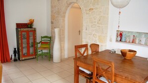 A dining area with a wooden table and chairs, a cabinet with glass doors, a stone wall, and a hanging light fixture.