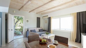 A modern living room with a wooden ceiling, a sofa, a coffee table, and a dining area with a table set for two. - Villa in Samos near Aghia Paraskevi Beach (Aghia Paraskevi)