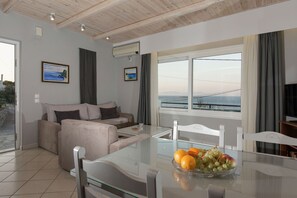 Relax in this stylish living area with a glass-top dining table, comfortable sofa, and a view of the sea and distant mountains.