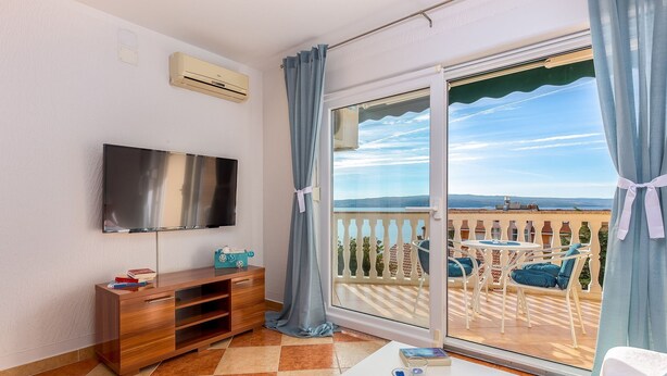 Un balcon avec un téléviseur, une armoire en bois et une table sur laquelle se trouvent un livre et des lunettes.