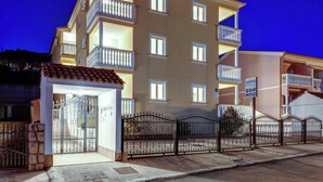 Un edificio de varios pisos con balcones, una entrada con reja y un letrero que indica que es un complejo de apartamentos.