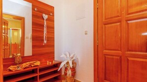 A wooden hallway with a large mirror, a wooden bench, a vase with white flowers, and a wooden door. - Holiday Home in Croatia near Scenic Beach (Dramalj)