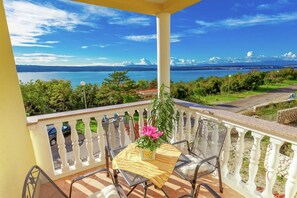 Ein Balkon mit Tisch, Stühlen und einer Topfpflanze.