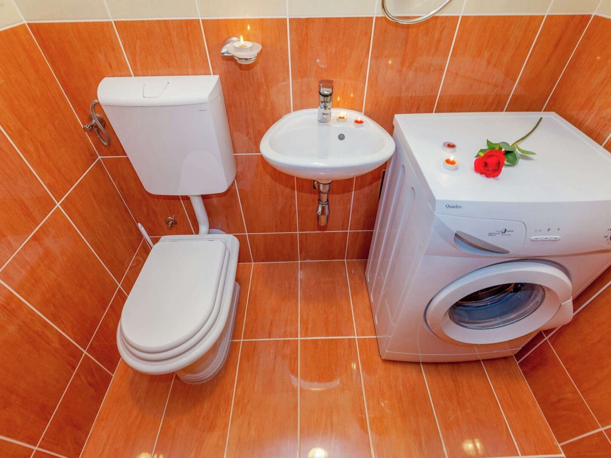 A bathroom with a toilet, sink, and washing machine.