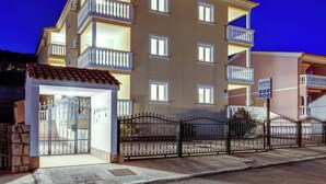 Un edificio de varios pisos con balcones, una entrada protegida por un portón y un letrero que indica que es un complejo de apartamentos.