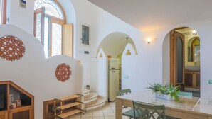 Amplia sala de estar con una mesa de comedor, sillas y una cocina al fondo.