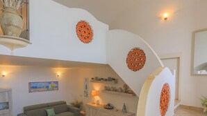 Amplia sala de estar con sofá, mesa de comedor y escalera con paneles decorativos.